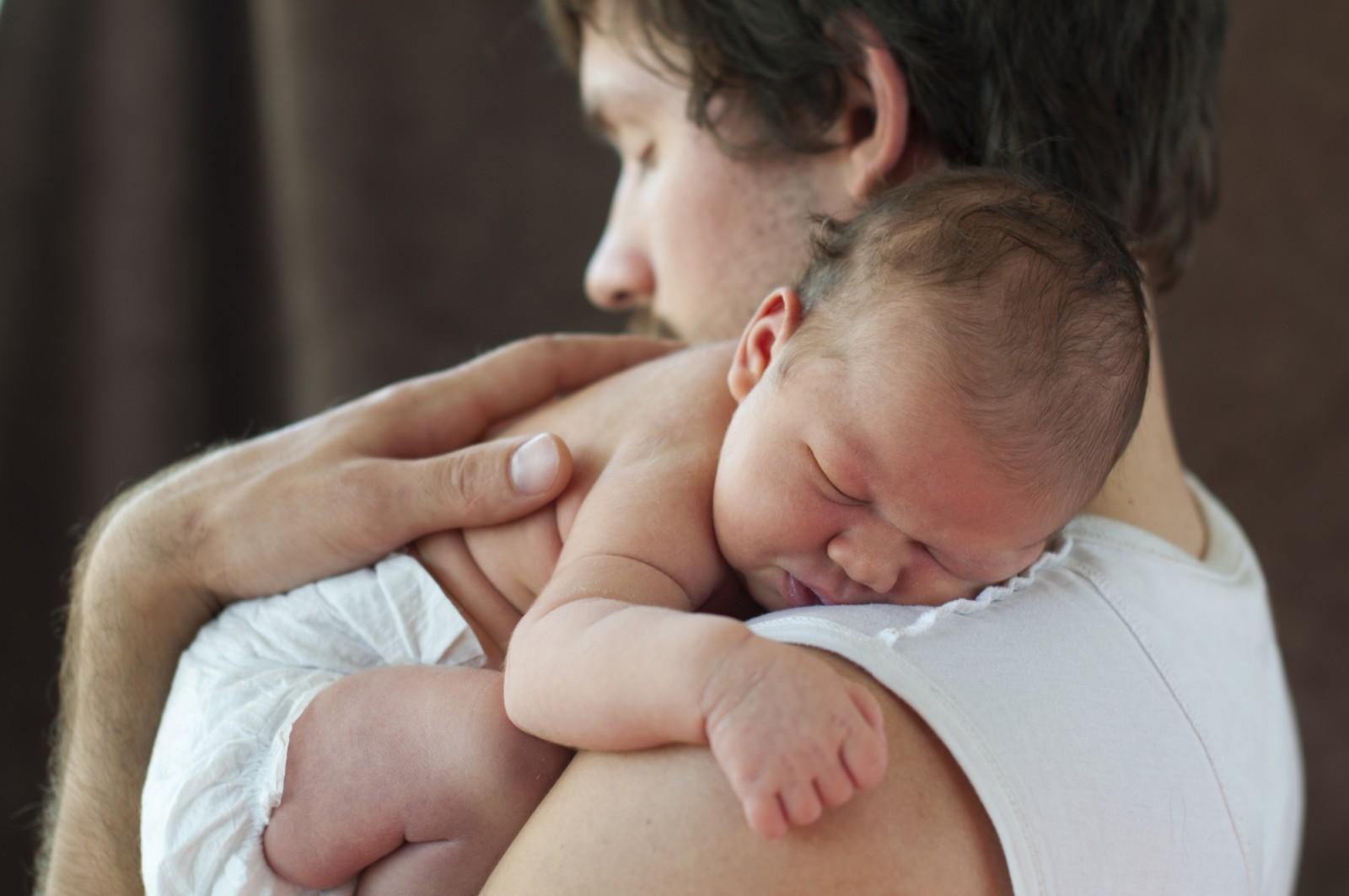 Ein Vater kuschelt mit seinem neu geborenen Kind © Shutterstock