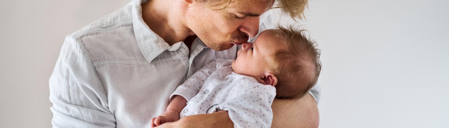 Ein Vater hält sein neugeborenes Kind auf dem Arm und gibt ihm einen Kuss auf die Nase © Shutterstock
